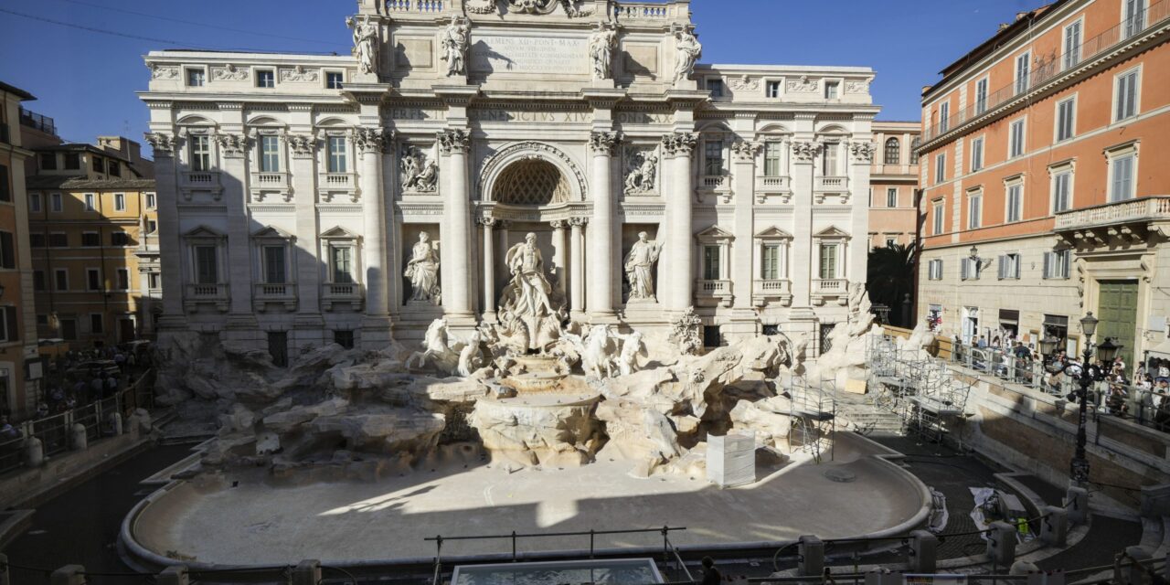 Tourists toss coins over a makeshift pool as Rome’s Trevi Fountain undergoes maintenance