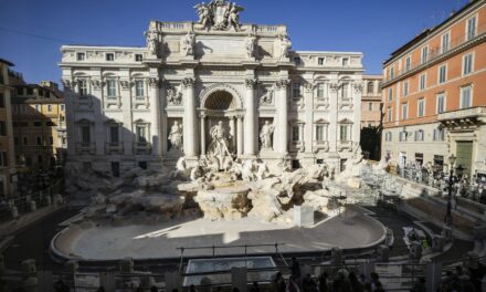 Tourists toss coins over a makeshift pool as Rome’s Trevi Fountain undergoes maintenance